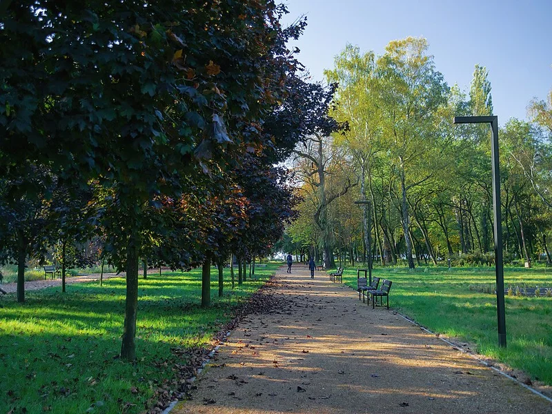 Personas caminando por un parque urbano al amanecer